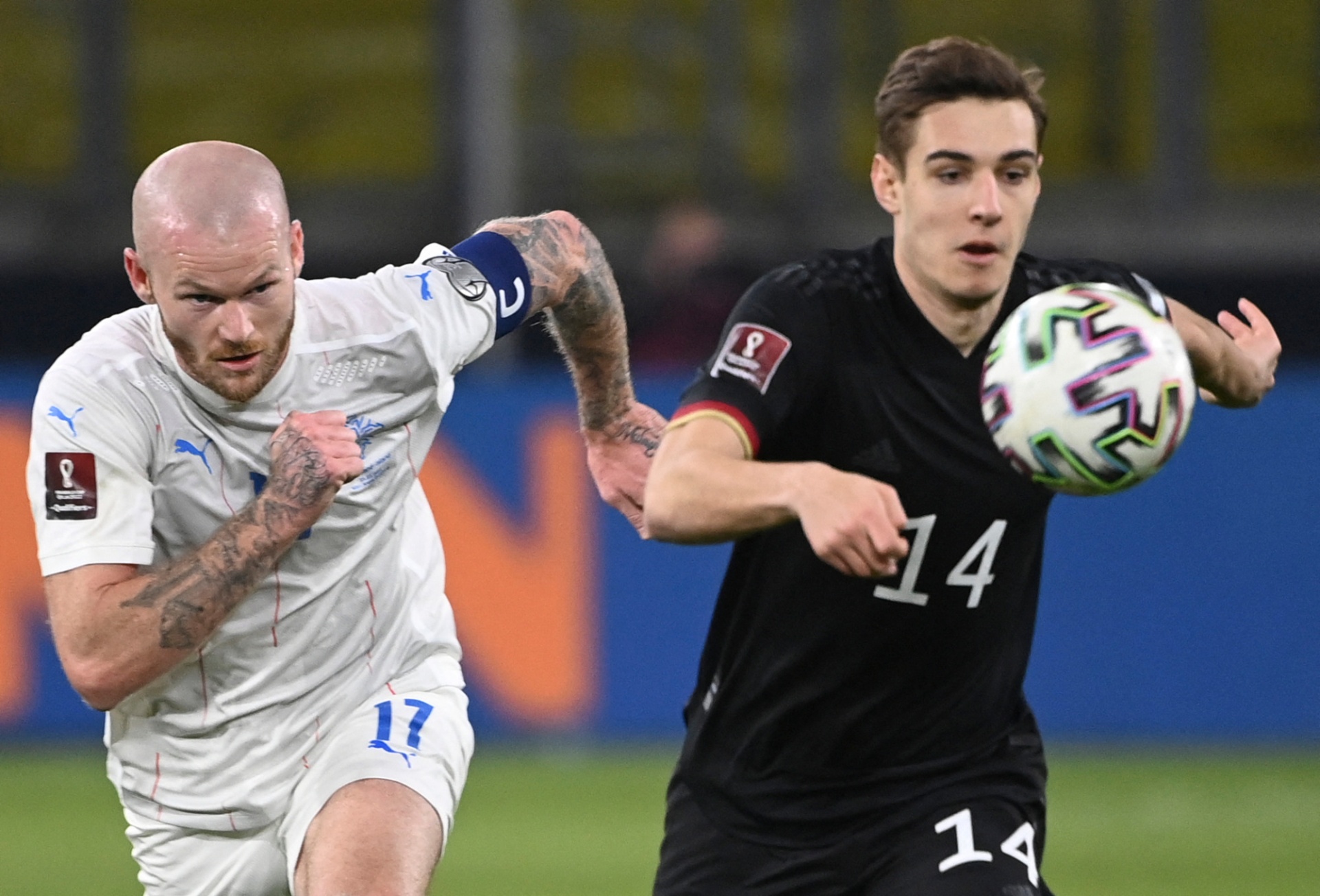 [{"clang_id":1,"value":"Zwei Fußballspieler im Spiel. Links ein Spieler mit Glatze und Tattoos, Trikotnummer 17. Rechts ein Spieler mit Trikotnummer 14, der den Ball führt."}]