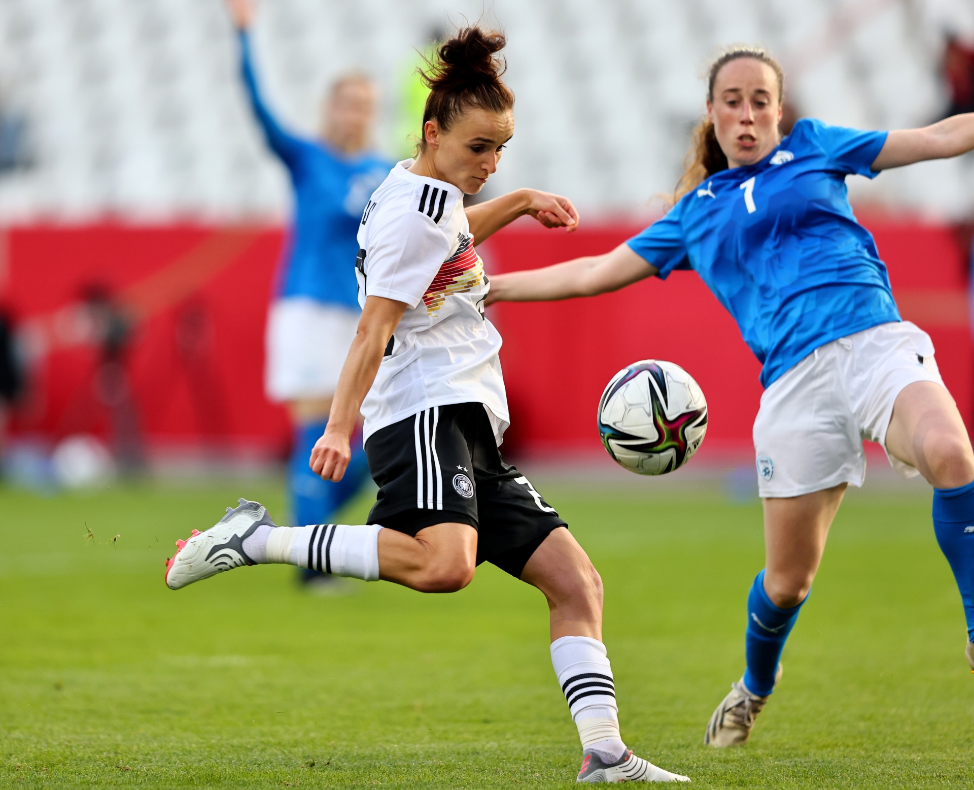 [{"clang_id":1,"value":"Fußballspiel: Spielerin mit weiß-schwarzem Trikot schießt Ball. Gegnerin in blauem Trikot versucht Ball zu blocken. Rasenplatz im Hintergrund."}]