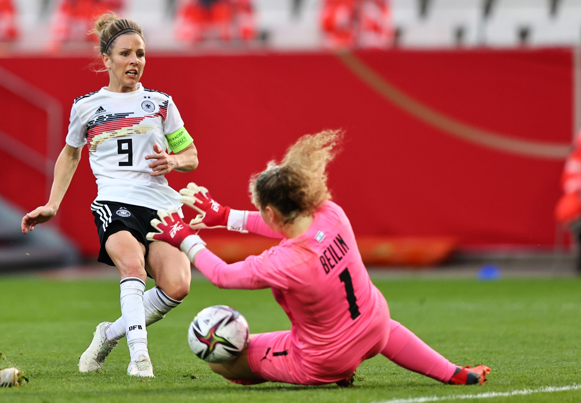[{"clang_id":1,"value":"Fußballspiel: Spielerin mit Trikotnummer 9 schießt aufs Tor, Torwartin mit Nummer 1 versucht den Ball zu halten. Rasen im Vordergrund."}]