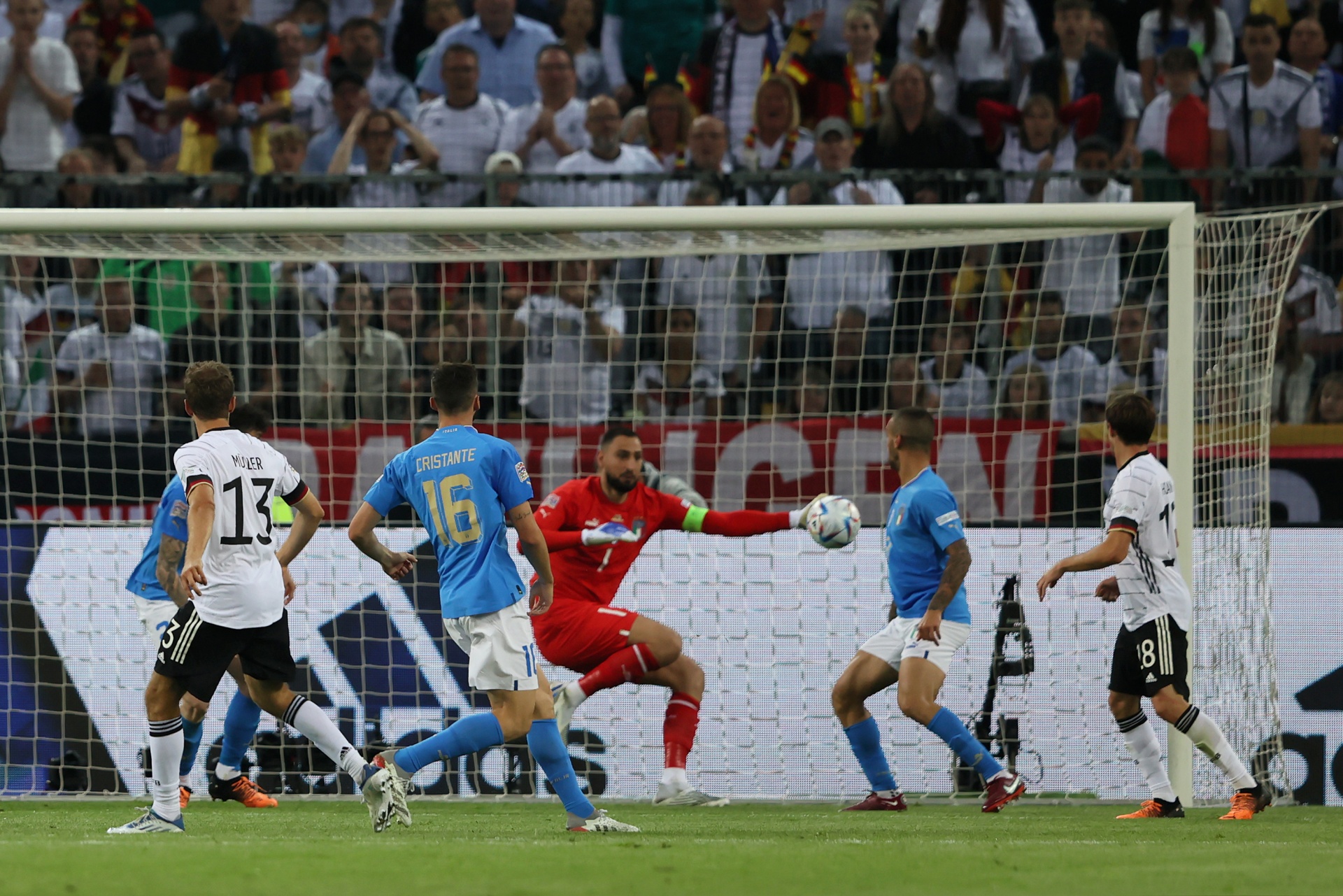 [{"clang_id":1,"value":"Fußballspiel: Deutschland in weißen Trikots gegen Chile in blauen. Spieler kämpfen um den Ball vor dem Tor, im Hintergrund Zuschauer."}]