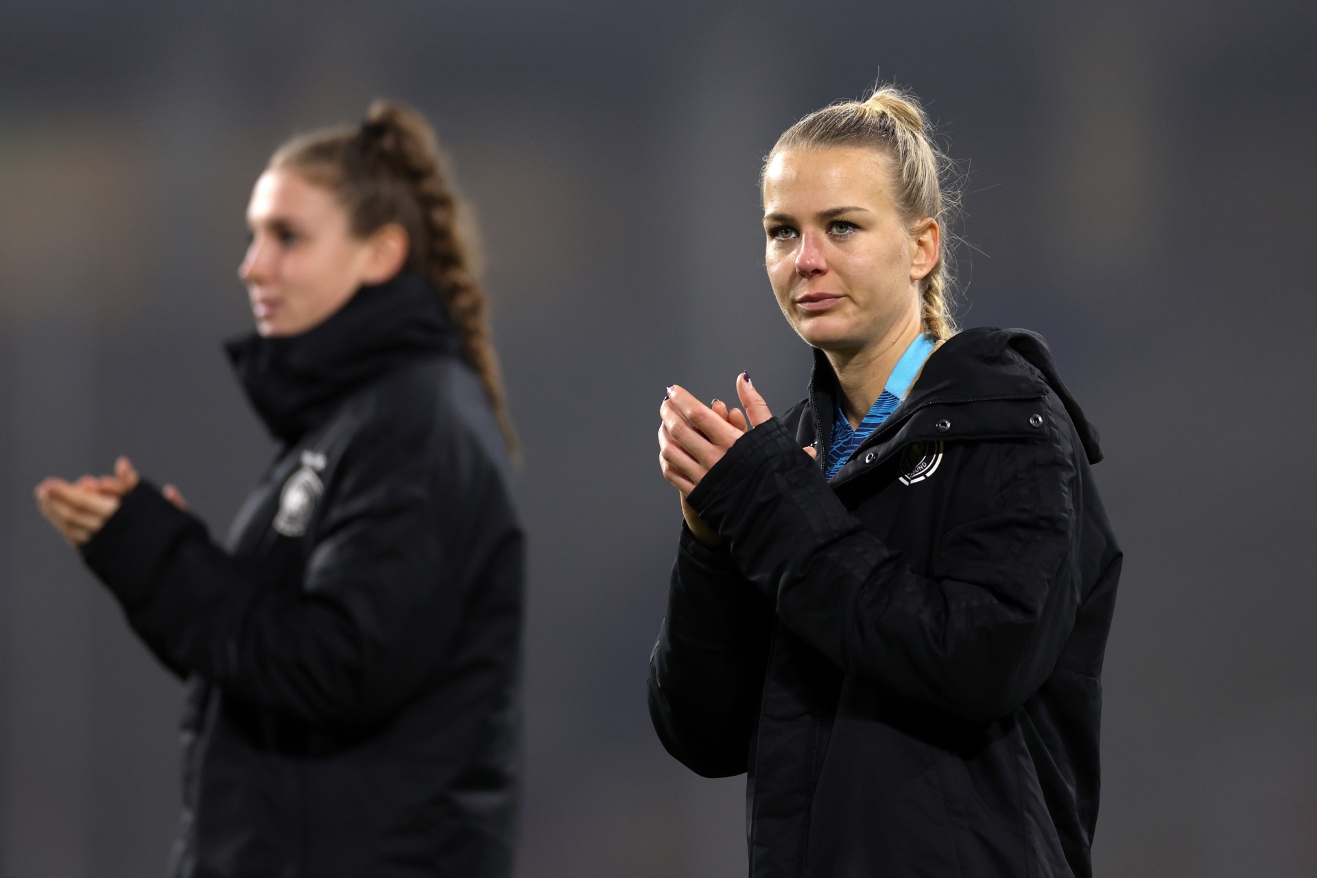 [{"clang_id":1,"value":"Zwei Sportlerinnen im schwarzen Trainingsanzug klatschen in der Hand. Im Hintergrund ein grauer, unscharfer Hintergrund."}]