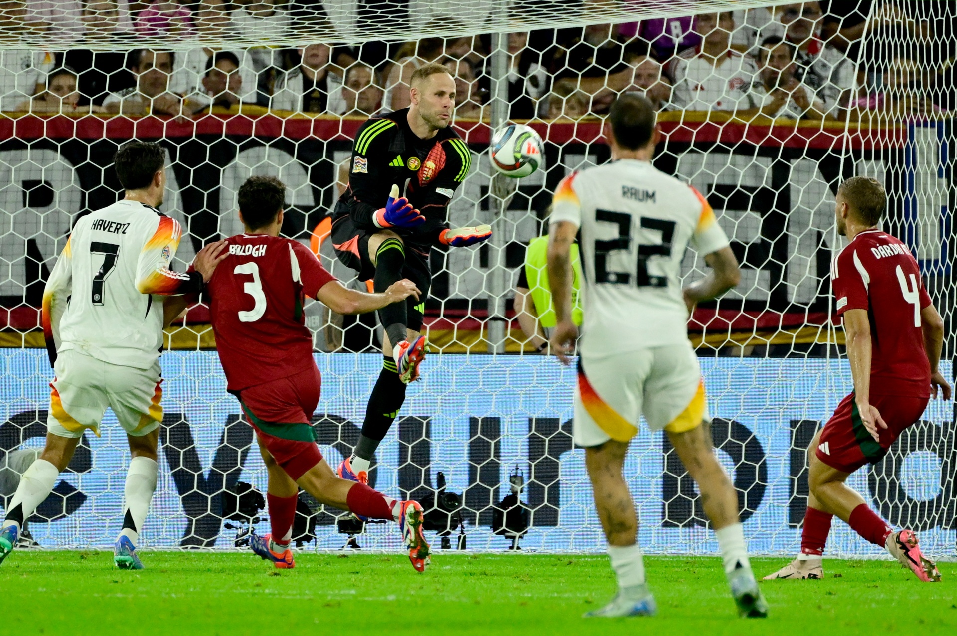 [{"clang_id":1,"value":"Fußballspiel: Spieler in weißen und roten Trikots kämpfen um den Ball vor dem Tor. Der Torwart springt, um den Ball zu halten. Im Hintergrund Zuschauer."}]