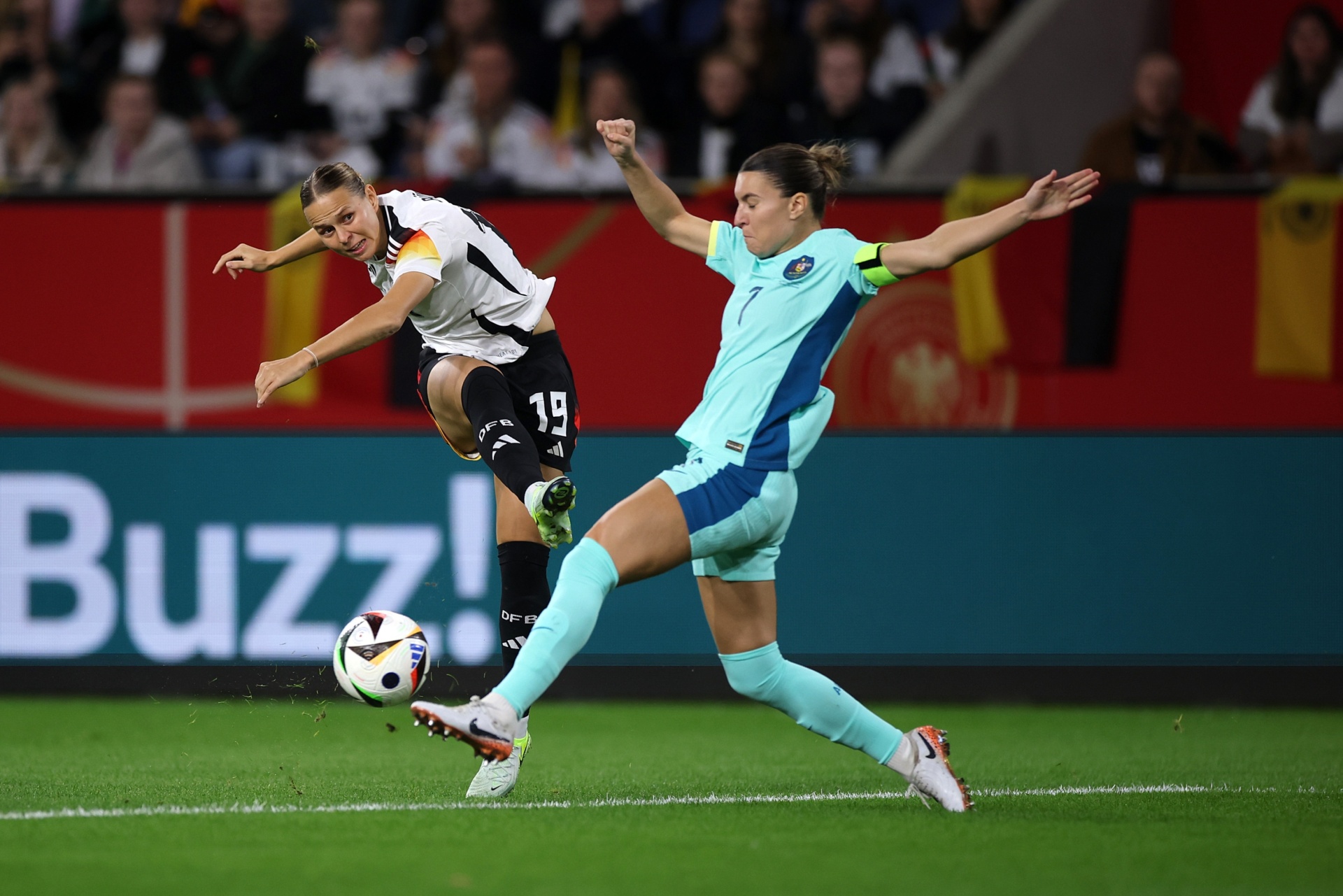 [{"clang_id":1,"value":"Zwei Fußballspielerinnen in Aktion. Links in schwarz-weiß, springt zur Ballkontrolle. Rechts in hellblau, grätscht dem Ball entgegen. Fußballfeld im Hintergrund."}]