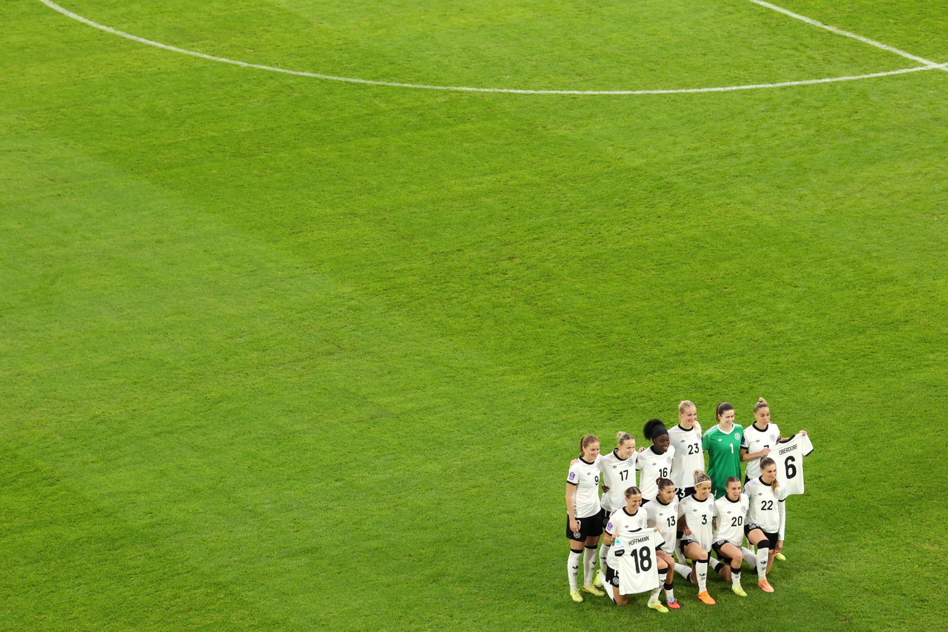 [{"clang_id":1,"value":"Fußballmannschaft in weißen Trikots steht auf grünem Rasen eines Stadions. Spieler tragen Nummern von 3 bis 23. Im Hintergrund Stadiontribünen."}]