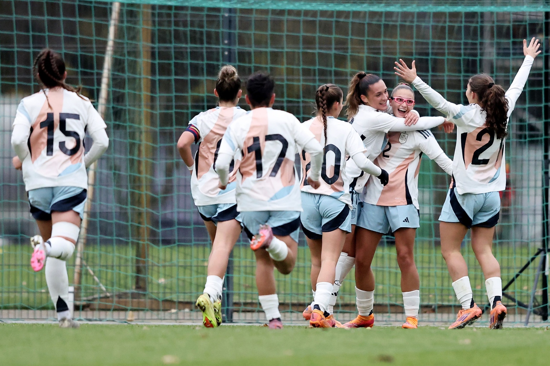 [{"clang_id":1,"value":"Fußballspiel: Frauenmannschaft in hellen Trikots und Shorts jubelt gemeinsam auf einem Rasenplatz. Rückennummern sind sichtbar. Im Hintergrund ein Zaun."}]
