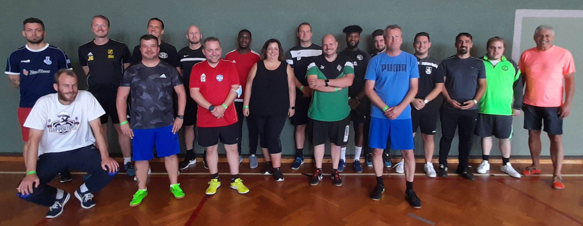 [{"clang_id":1,"value":"Mannschaftsfoto: 23 Personen stehen in einem hellen Raum mit Sportboden vor einer hellgrauen Wand. Sie tragen Sportkleidung in verschiedenen Farben."}]