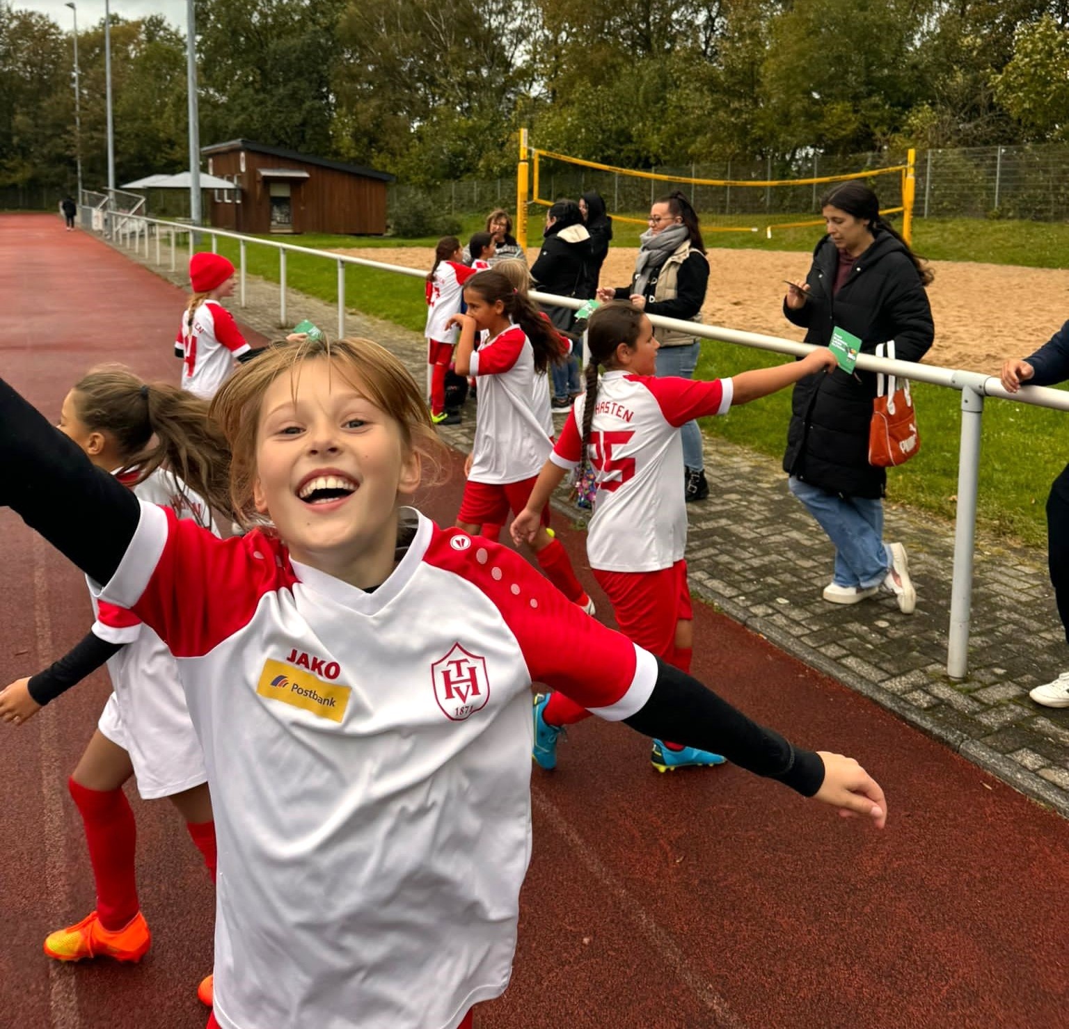 [{"clang_id":1,"value":"Junge im Fußballtrikot mit ausgestreckten Armen, jubelnd. Im Hintergrund weitere Fußballspieler und Zuschauer am Spielfeldrand."}]