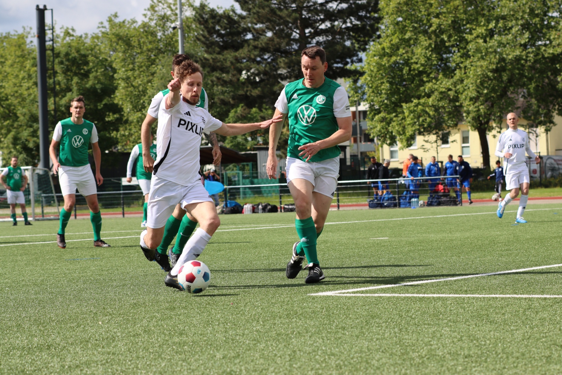 [{"clang_id":1,"value":"Fußballspiel: Zwei Spieler dribbeln den Ball auf einem grünen Rasenplatz. Im Hintergrund weitere Spieler und Zuschauer."}]