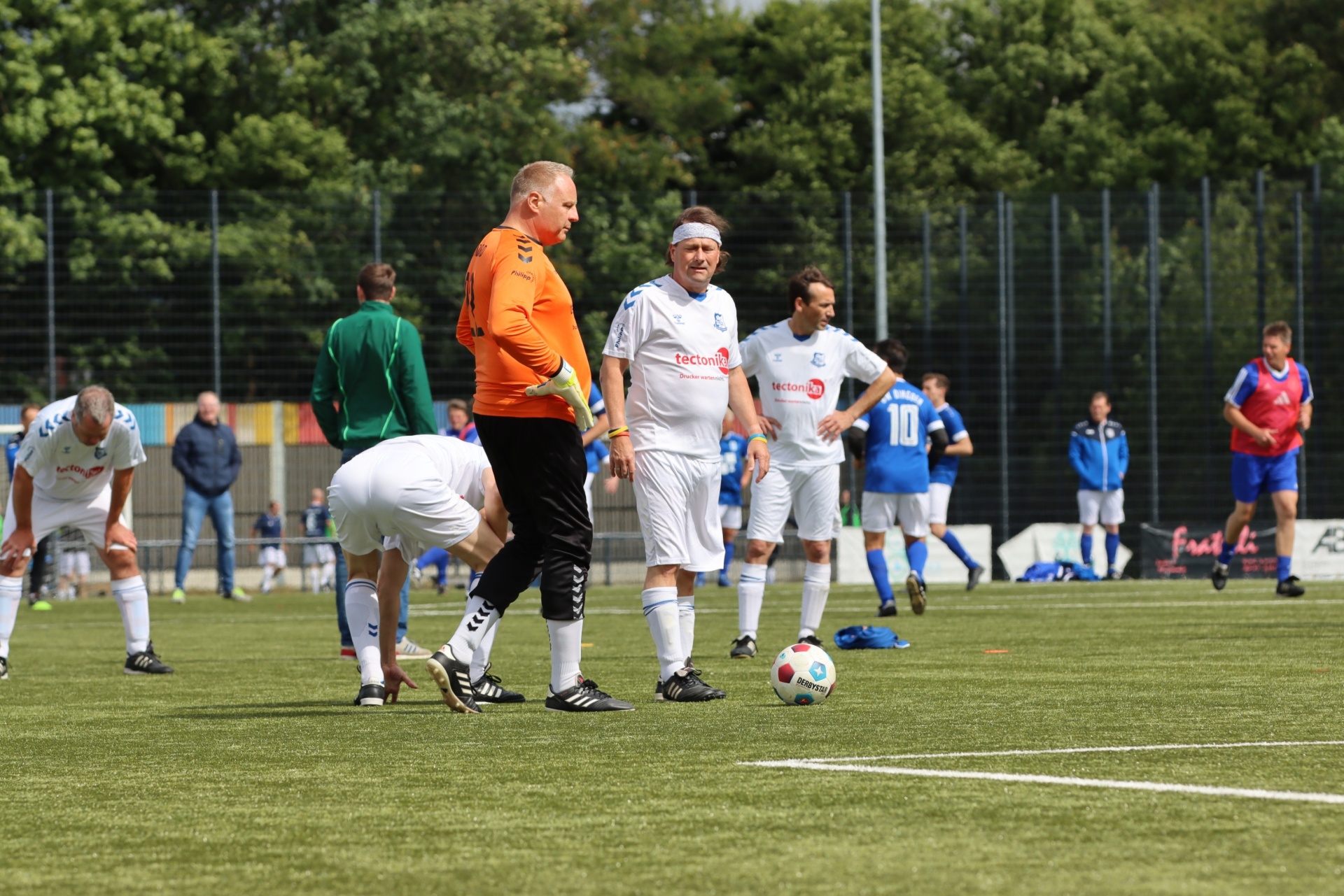 [{"clang_id":1,"value":"Fußballfeld mit Spielern in weißen und blauen Trikots. Ein Torwart in schwarzer und gelber Kleidung steht am Rand des Spielfelds. Zuschauer im Hintergrund."}]
