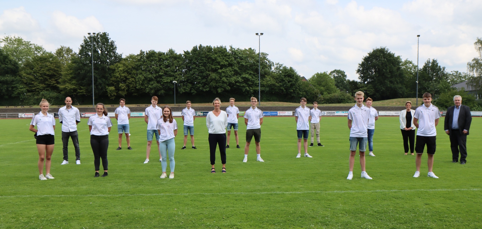 [{"clang_id":1,"value":"Gruppe von etwa 15 jungen Menschen und ein älterer Mann stehen auf einem Fußballfeld. Sie tragen sportliche Kleidung und schauen in die Kamera."}]