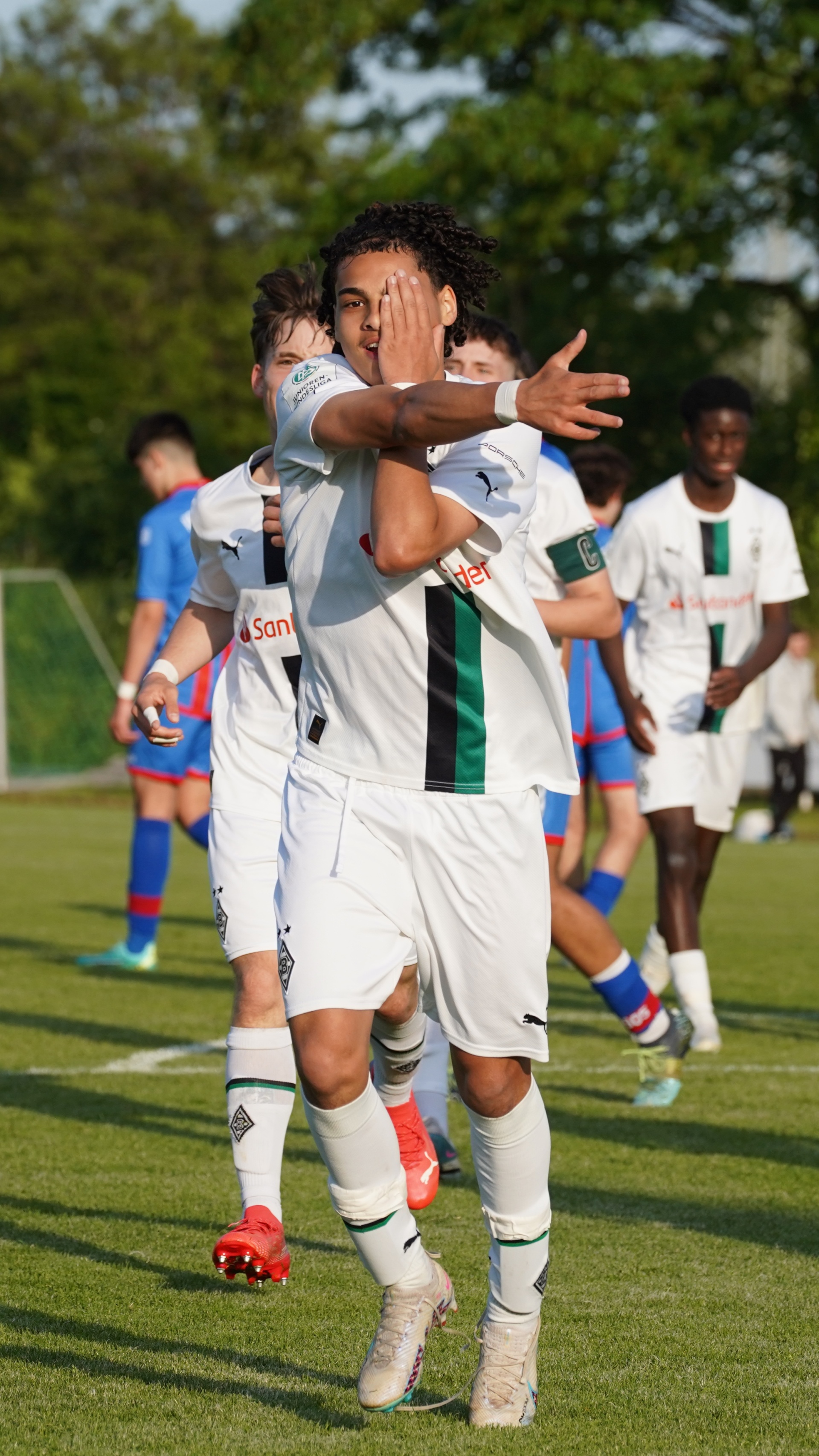 [{"clang_id":1,"value":"Fußballspieler feiert mit hochgestreckten Armen auf grünem Rasen. Er trägt ein weiß-grün-schwarzes Trikot. Im Hintergrund weitere Spieler."}]