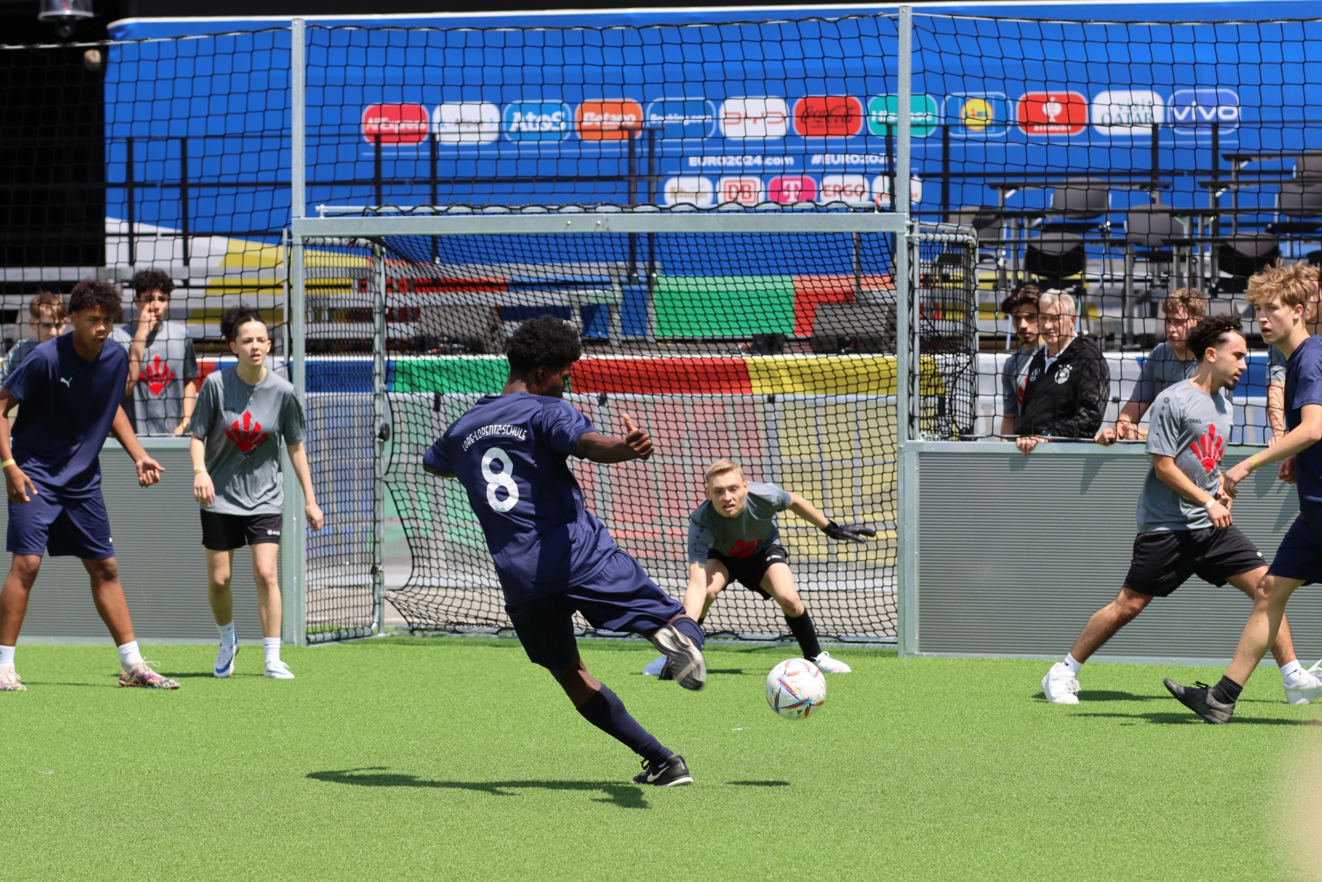 [{"clang_id":1,"value":"Fußballtraining: Junge kicken Ball auf kleines Tor. Im Hintergrund weitere Spieler und Zuschauer, Werbebanner im Hintergrund."}]