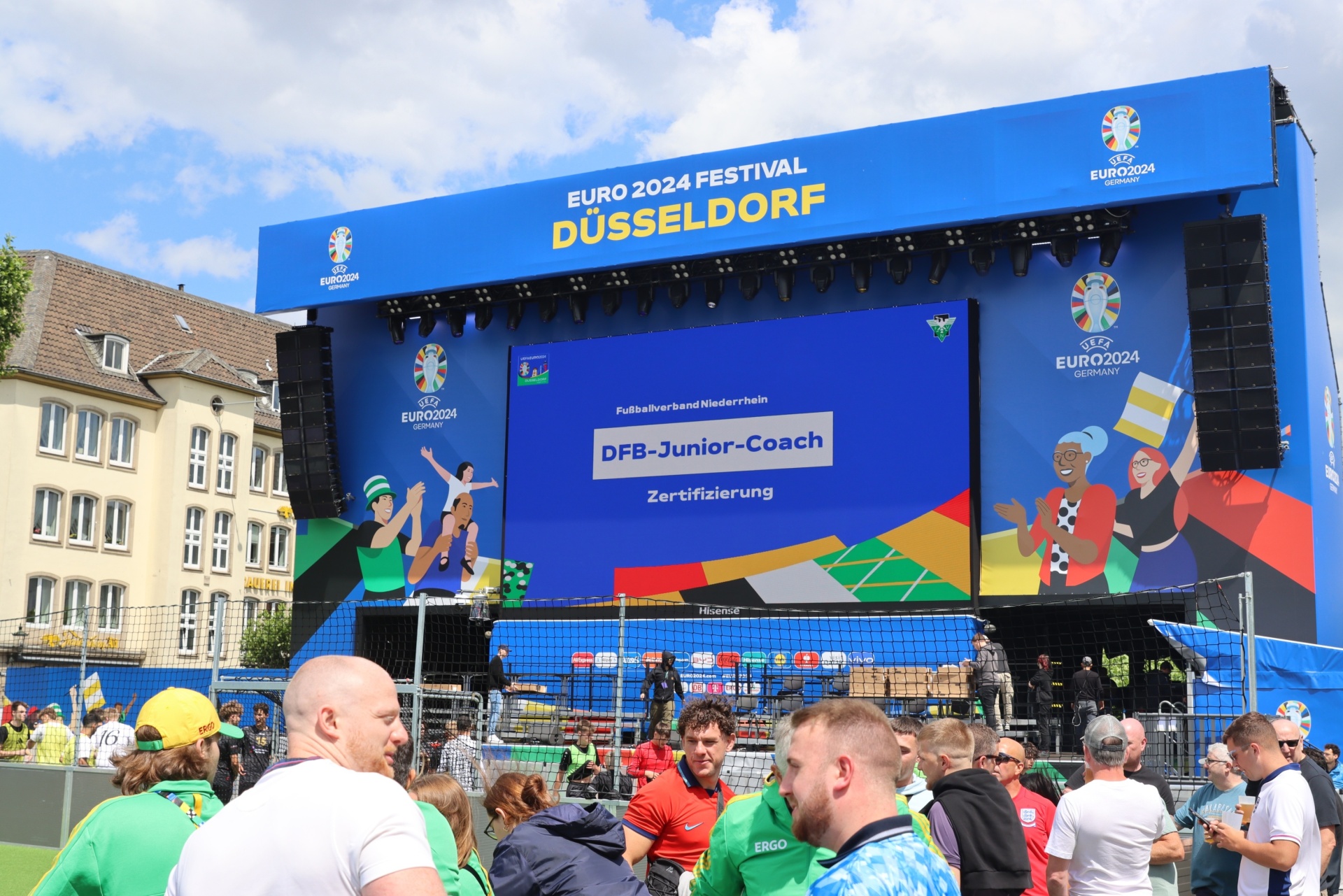 [{"clang_id":1,"value":"Bühne mit Aufschrift \"EURO 2024 Festival Düsseldorf\". Davor Menschenmenge, im Hintergrund Gebäude und blauer Himmel."}]