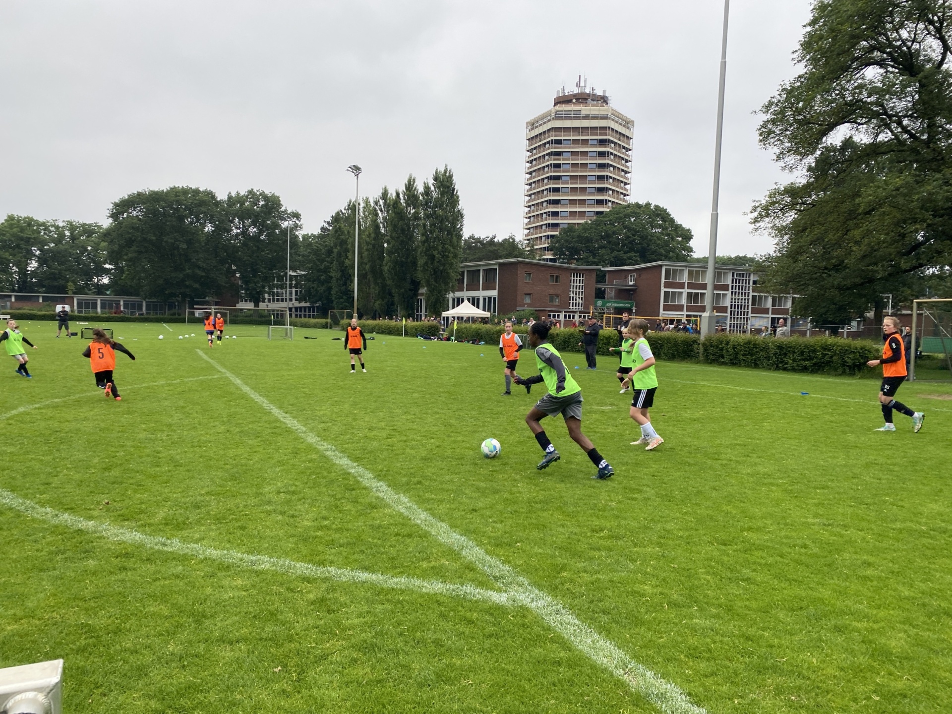 [{"clang_id":1,"value":"Jugendfußballspiel auf Grasplatz. Spieler in orange und dunkelblauen Trikots, Hintergrund: Gebäude und Bäume."}]