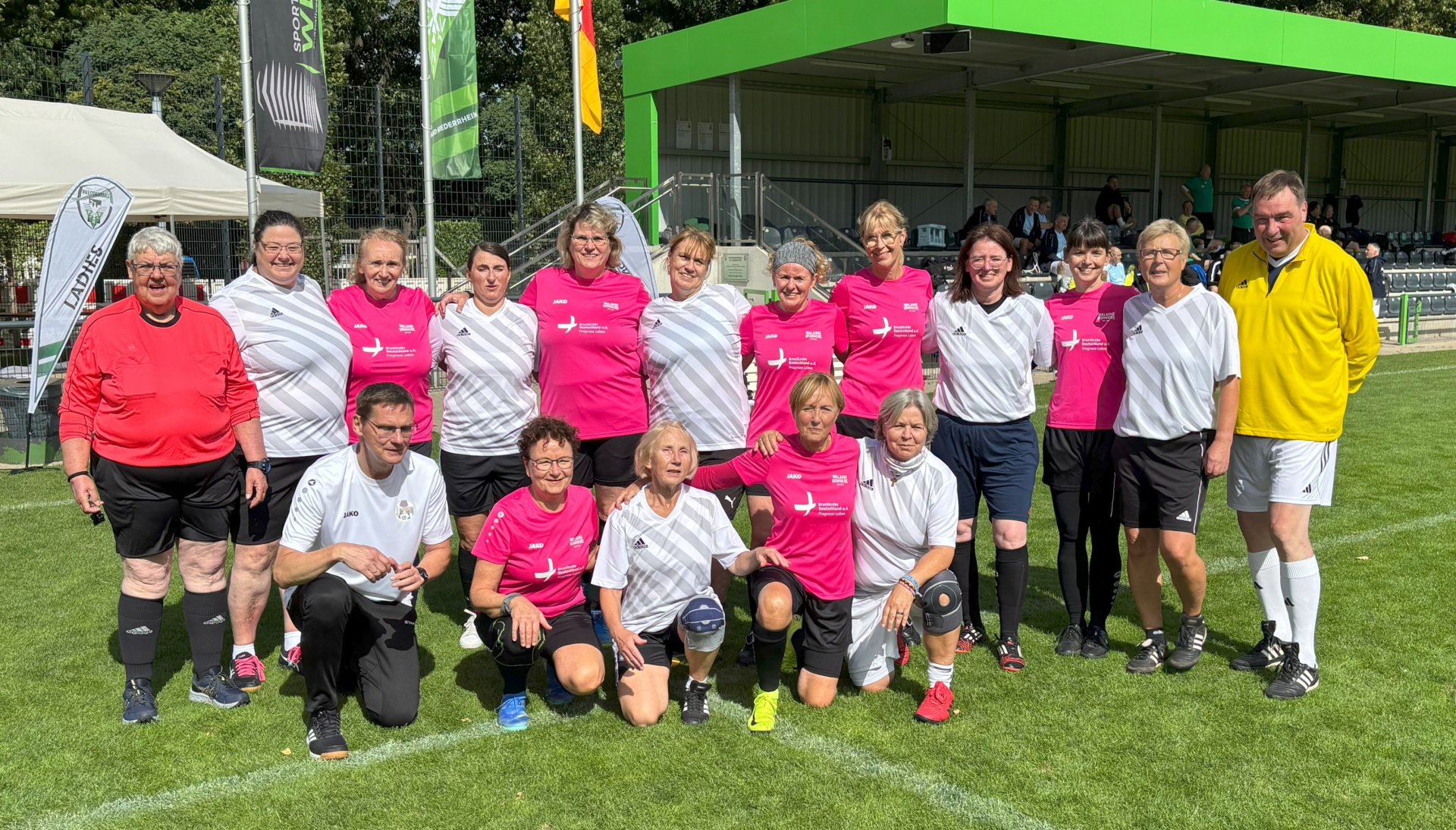 [{"clang_id":1,"value":"Fußballmannschaft in Vereinskleidung steht auf einem Fußballfeld. Im Hintergrund ein Stadiongebäude und grüne Bäume. Zwei Schiedsrichter stehen am Rand."}]