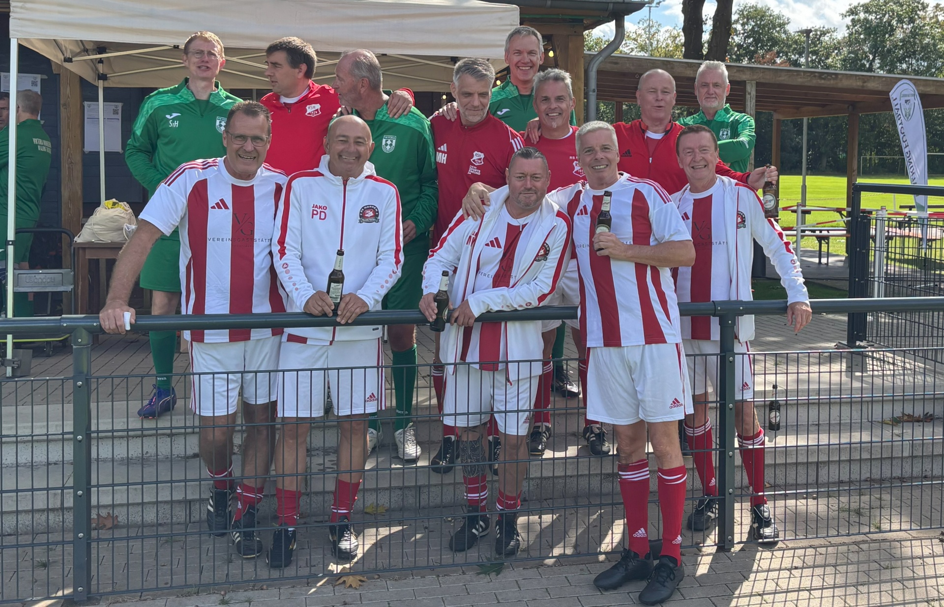[{"clang_id":1,"value":"Fußballmannschaft in rot-weißen Trikots und weißen Shorts posiert lächelnd vor einem Vereinsheim. Einige halten Bierflaschen. Im Hintergrund grüner Rasen und Bäume."}]