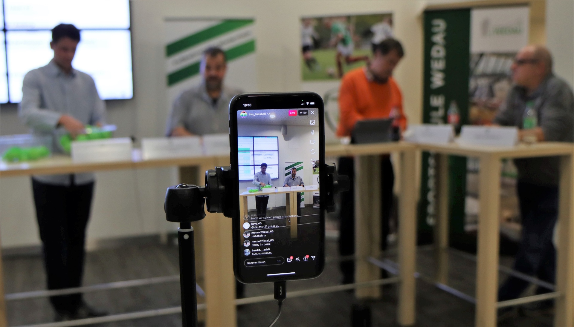 [{"clang_id":1,"value":"Innenraum, Konferenz. Smartphones auf Stativen vor Tischen. Menschen sitzen an den Tischen, einige blicken auf die Bildschirme. Hintergrund ist unscharf."}]