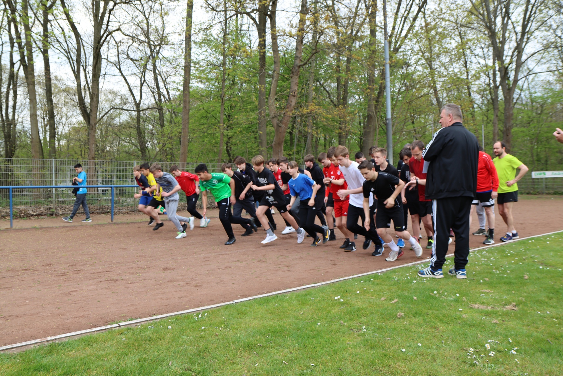 [{"clang_id":1,"value":"Gruppe Jugendlicher beim Laufen auf einer Tartanbahn, begleitet von erwachsenen Trainern. Im Hintergrund Bäume und eine Sportanlage."}]