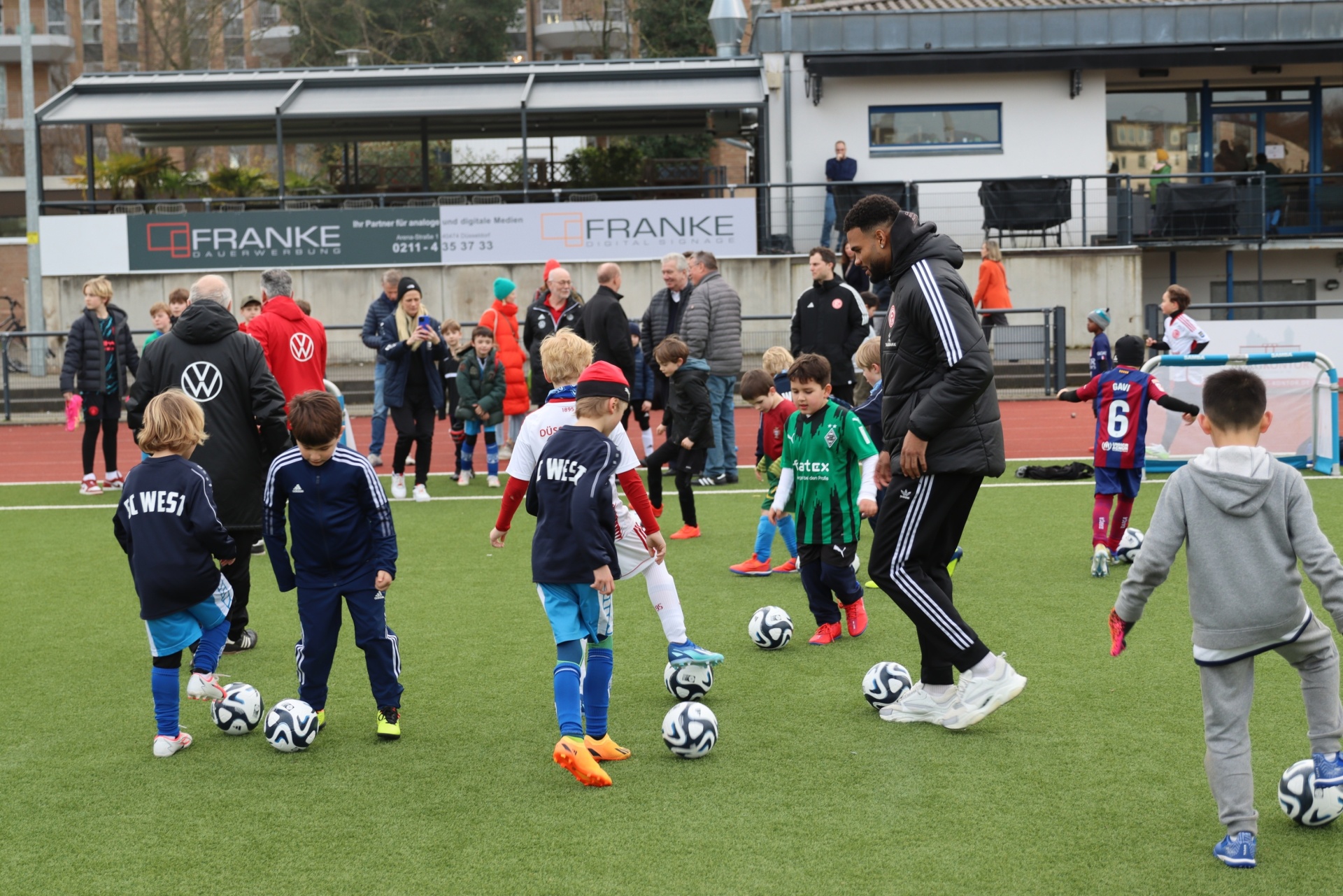 [{"clang_id":1,"value":"Fußballtraining mit Kindern und einem Trainer auf einem Kunstrasenplatz. Im Hintergrund Zuschauer und ein Stadion."}]