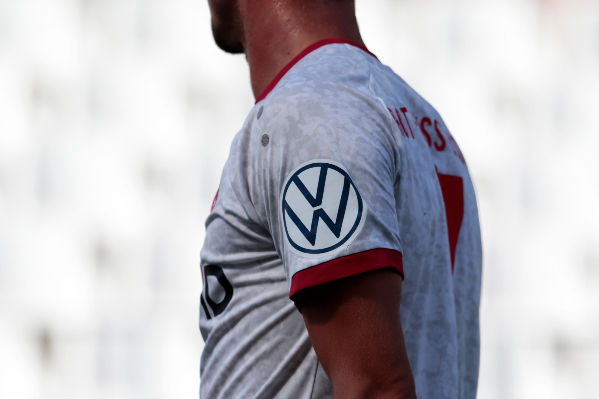 [{"clang_id":1,"value":"Rückansicht einer Person mit Fußballtrikot in Rot-Weiß. Auf dem Ärmel das Volkswagen-Logo. Verschwommener Hintergrund."}]