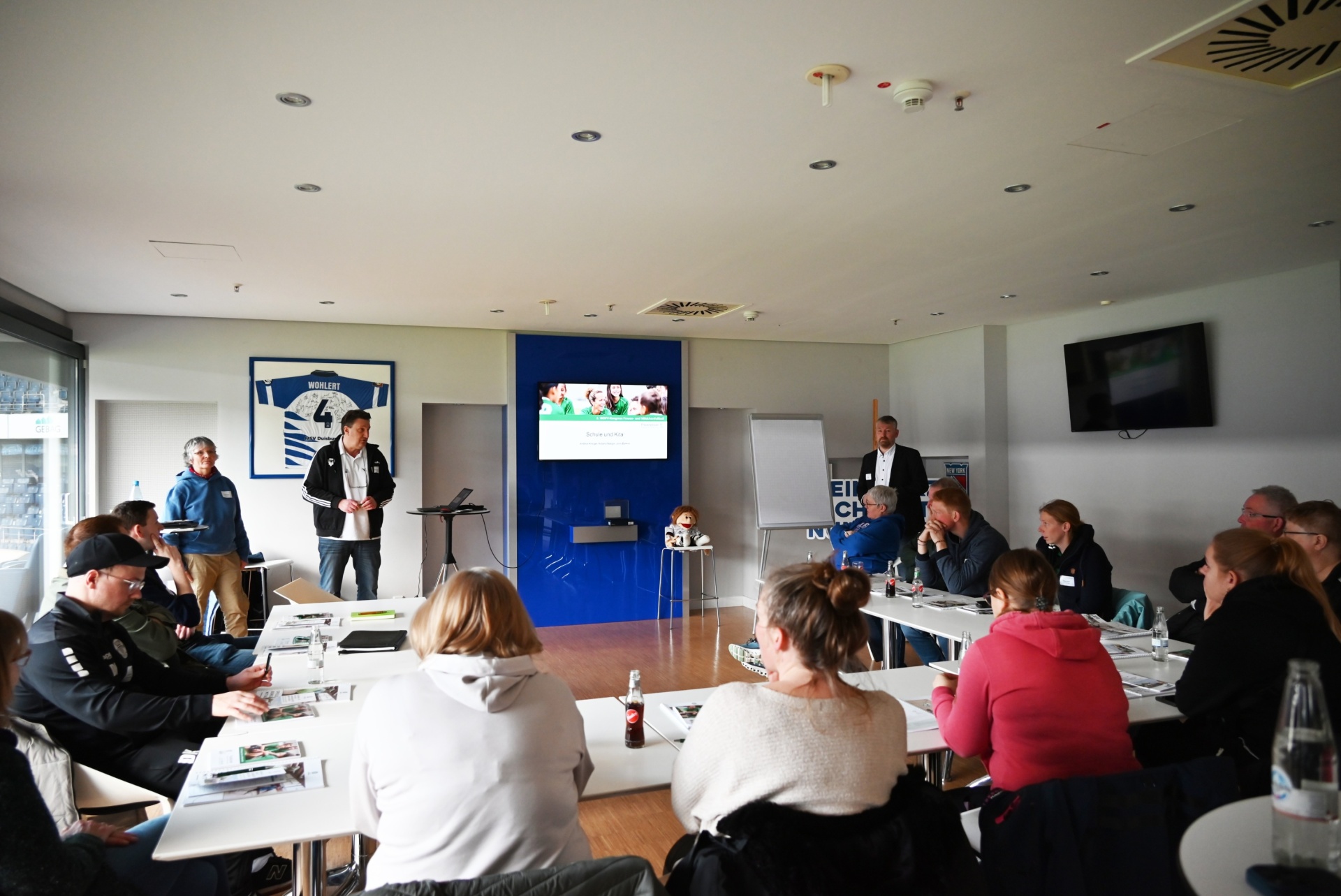 [{"clang_id":1,"value":"Raum mit Seminarteilnehmern, die an Tischen sitzen. Ein Mann steht vorne und hält einen Vortrag, ein anderer steht am Whiteboard."}]