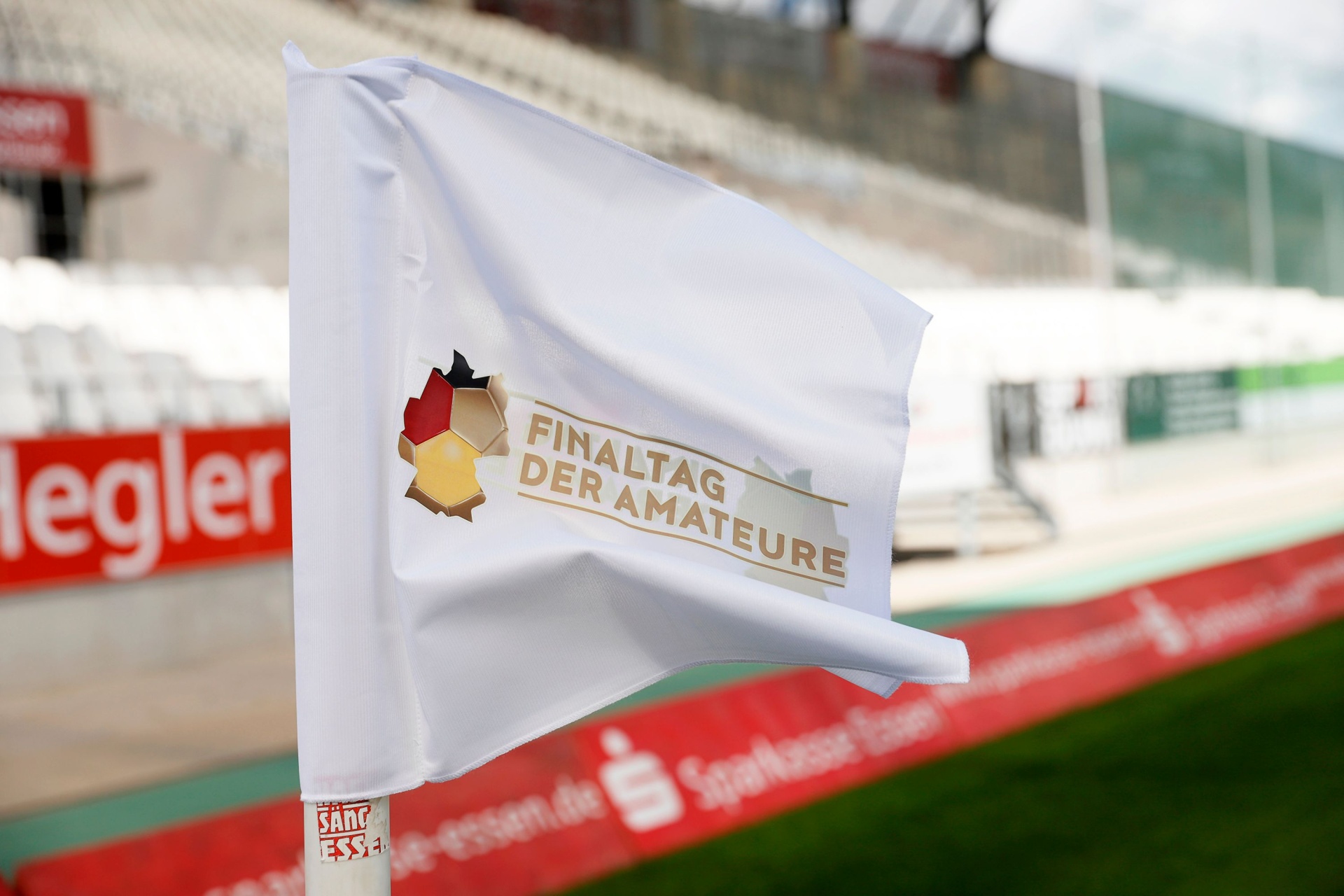 [{"clang_id":1,"value":"Wappen mit den Farben Deutschland, Hessen und einer Fußballkugel auf weißem Banner. Text: \"Finaltag der Amateure\". Im Hintergrund ein Stadion."}]