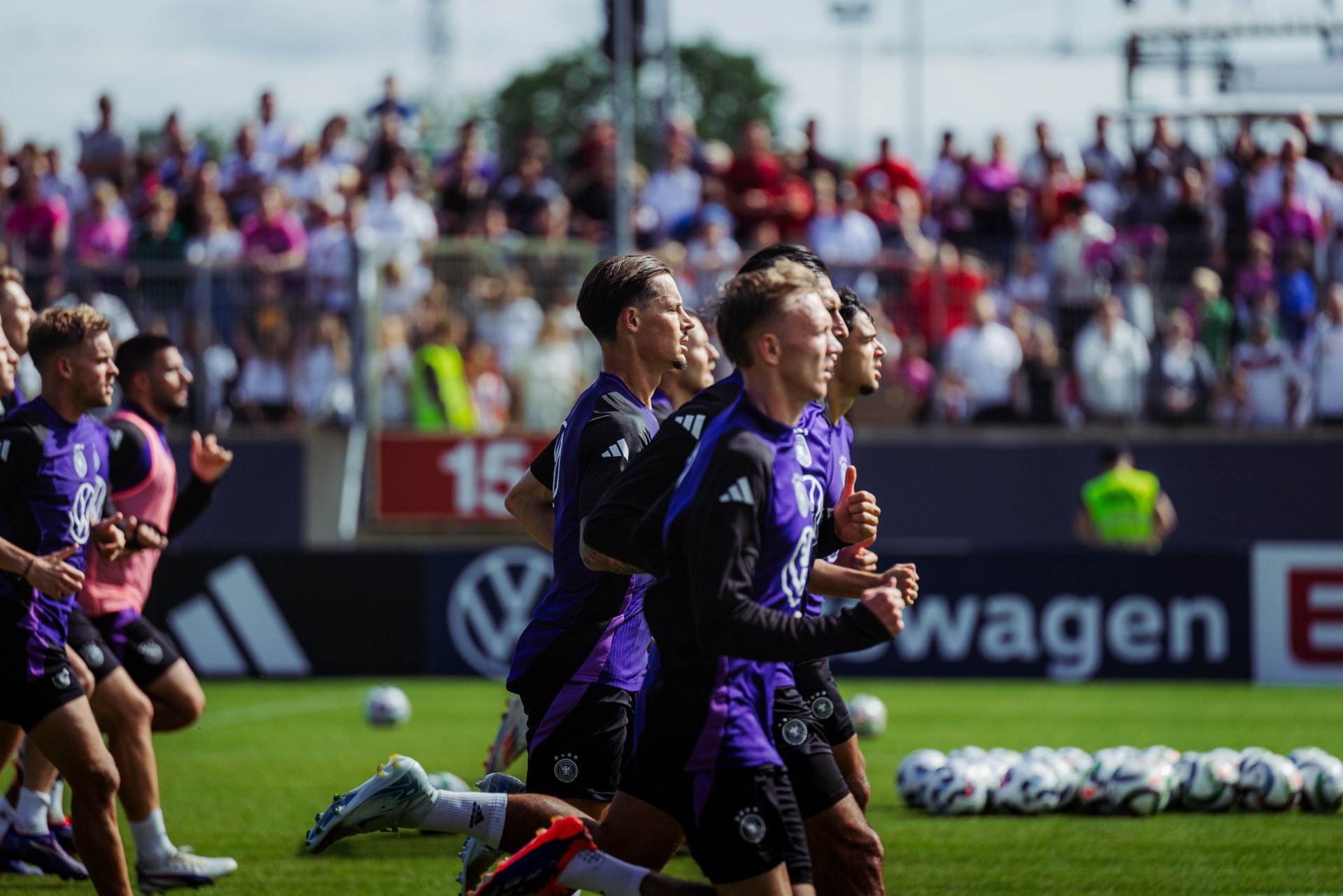 [{"clang_id":1,"value":"Fußballspieler in violetten Trikots jubeln auf grünem Rasen vor voll besetzter Tribüne. Im Hintergrund Werbebanner für Volkswagen."}]