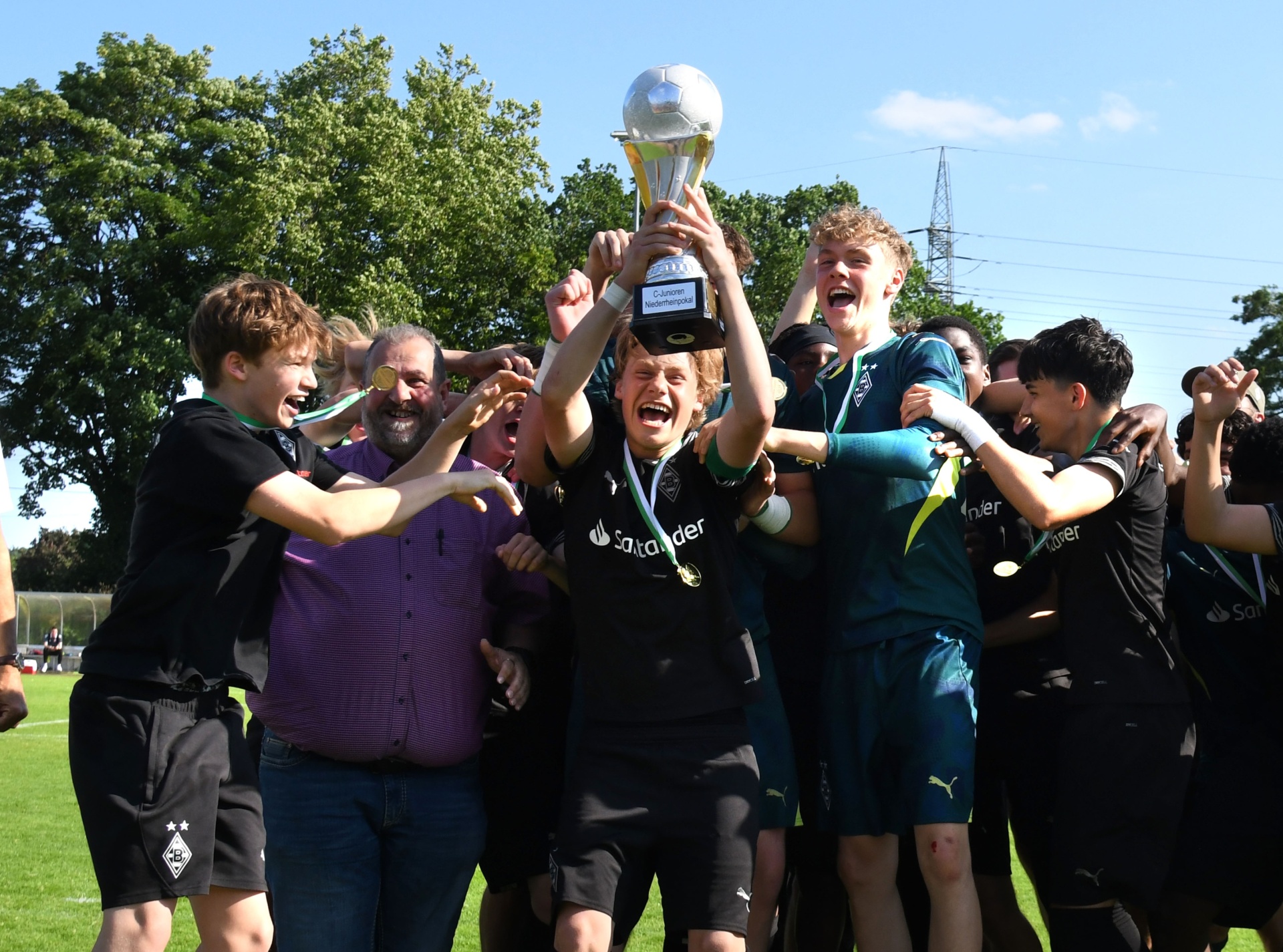 [{"clang_id":1,"value":"Fußballteam feiert Sieg mit Pokal. Spieler in dunklen Trikots und Shorts heben gemeinsam den silbernen Pokal hoch, umgeben von Betreuern und Zuschauern auf einem Fußballfeld."}]