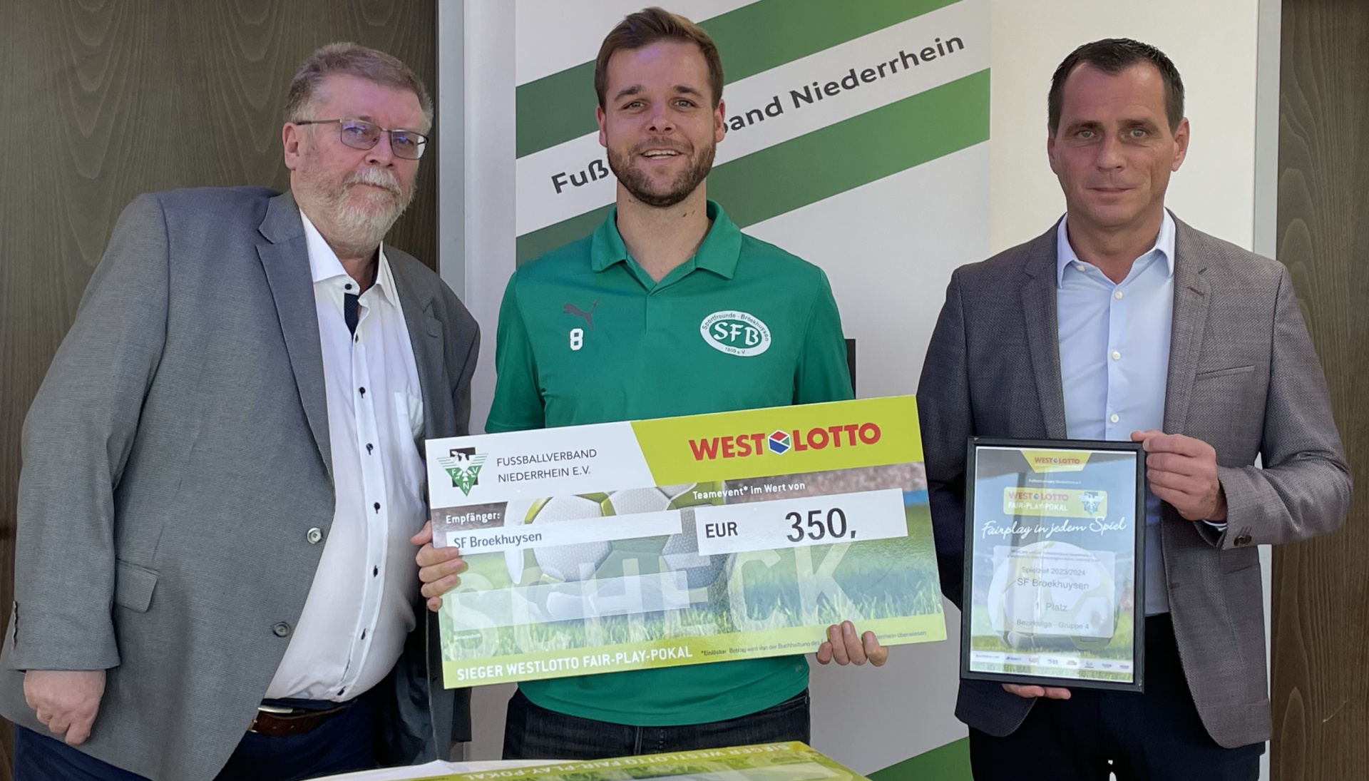 [{"clang_id":1,"value":"Drei Männer bei Preisverleihung. Mittlerer Mann mit Fußballtrikot hält Check und Urkunde, links und rechts stehen weitere Männer in Anzug. Im Hintergrund Banner."}]