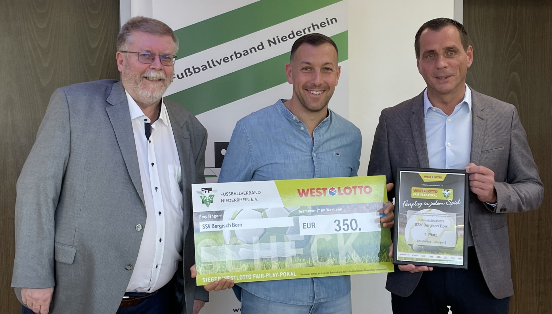 [{"clang_id":1,"value":"Drei Männer posieren mit einem übergroßen Scheck über 350 EUR und einer Urkunde. Im Hintergrund ein Banner mit dem Schriftzug \"Fußballverband Niederrhein\"."}]