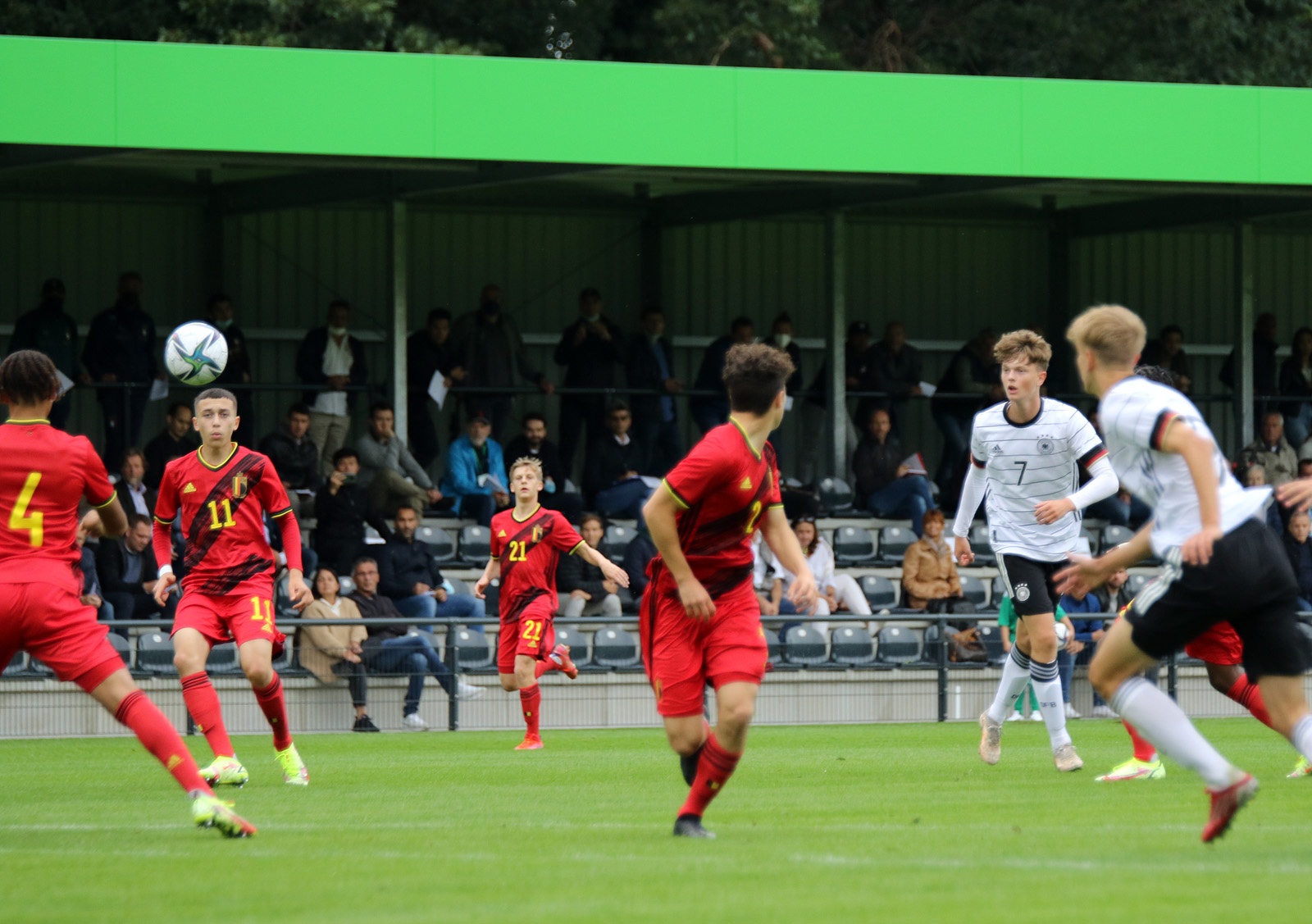 [{"clang_id":1,"value":"Fußballspiel: Spieler in rot und schwarz kämpfen um den Ball auf grünem Rasen. Im Hintergrund Zuschauertribünen mit Zuschauern."}]
