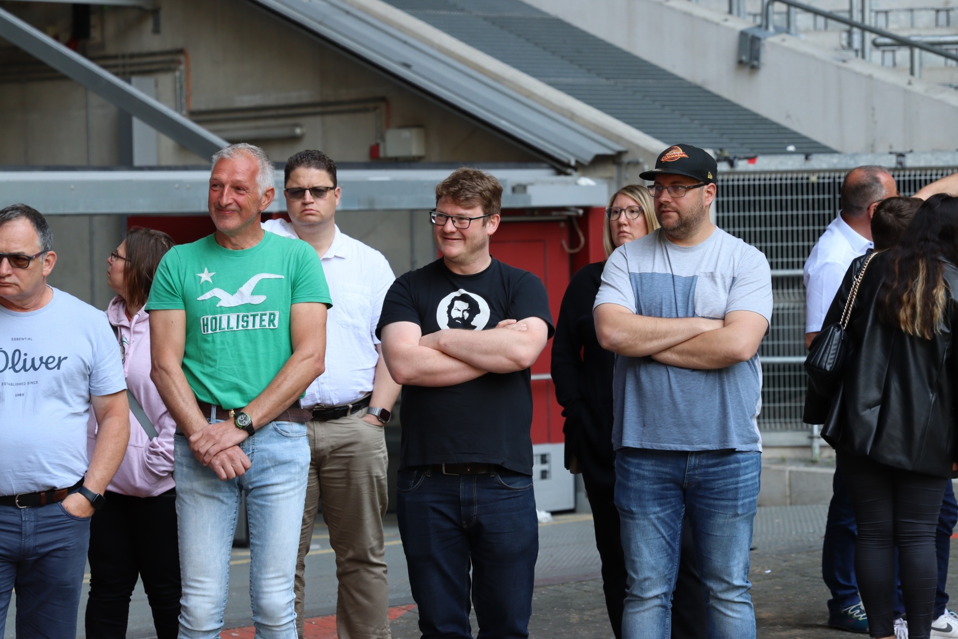 [{"clang_id":1,"value":"Gruppe von acht Personen steht im Freien vor Metallstufen. Sie tragen Freizeitkleidung, darunter T-Shirts und Jeans."}]