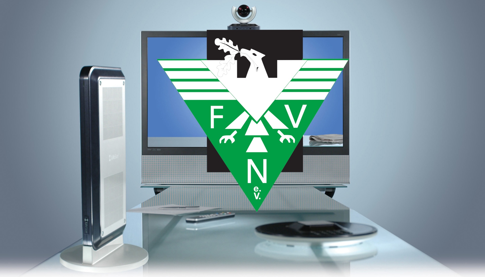 [{"clang_id":1,"value":"Flachbildfernseher zeigt grünes Dreieck mit weißem Adler und Schriftzug \"FAV N.V.\". Darunter eine Soundbar, davor Fernbedienung und CD/DVD. Links ein Luftreiniger."}]