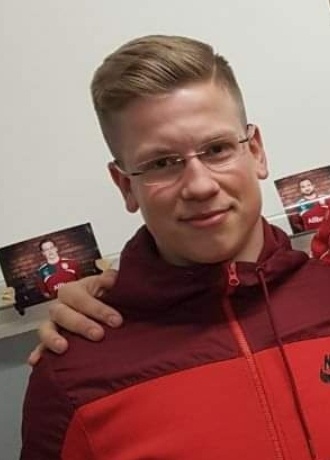 [{"clang_id":1,"value":"Mann mit Brille und roter Trainingsjacke lächelt in die Kamera. Im Hintergrund sind zwei Bilder von ihm in ähnlicher Kleidung zu sehen."}]