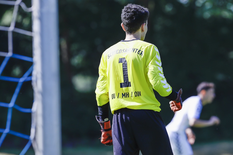[{"clang_id":1,"value":"Fußballtorwart mit gelbem Trikot und schwarzer Hose steht vor dem Tor. Rückansicht, Nummer 1 auf dem Rücken. Im Hintergrund verschwommene Spieler."}]