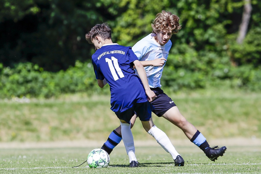 [{"clang_id":1,"value":"Zwei Fussballspieler kämpfen um den Ball auf einem grünen Rasenfeld. Spieler links trägt blaues Trikot mit Nummer 11, Spieler rechts blau-weisses Trikot. Hintergrund: Bäume."}]
