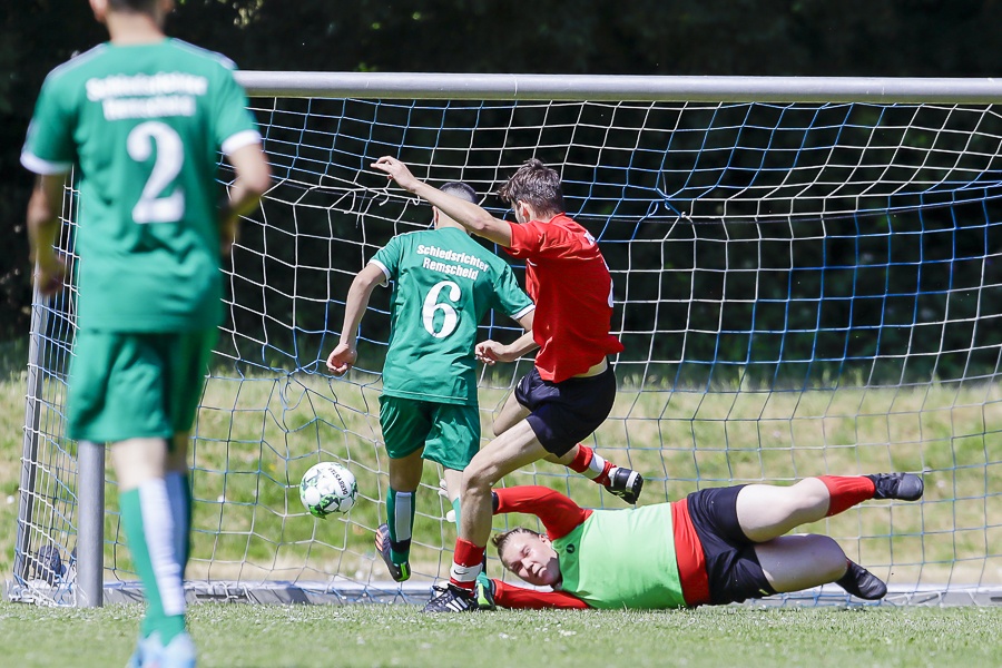 [{"clang_id":1,"value":"Fußballspiel: Zwei Spieler in Rot und Grün kämpfen vor dem Tor um den Ball. Ein Torwart in grün liegt am Boden. Grasplatz und Fußballnetz im Hintergrund."}]