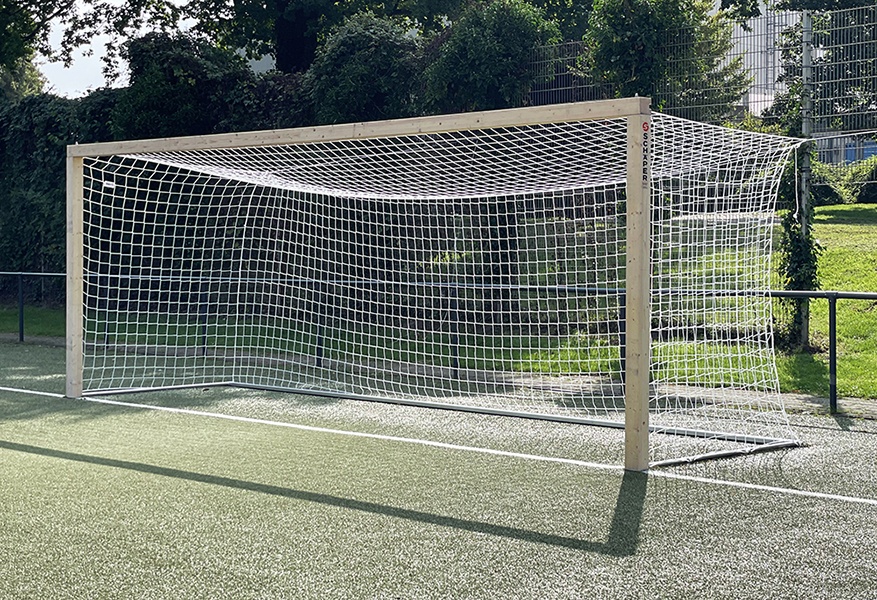[{"clang_id":1,"value":"Fußballtor auf grünem Kunstrasenplatz. Das Tor hat einen Holzrahmen und ein weißes Netz. Im Hintergrund Begrünung und ein Zaun."}]