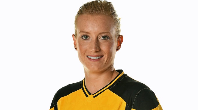 [{"clang_id":1,"value":"Frau mit blonden, kurzen Haaren, lächelnd, trägt gelb-schwarzes Sporttrikot. Weißer Hintergrund."}]